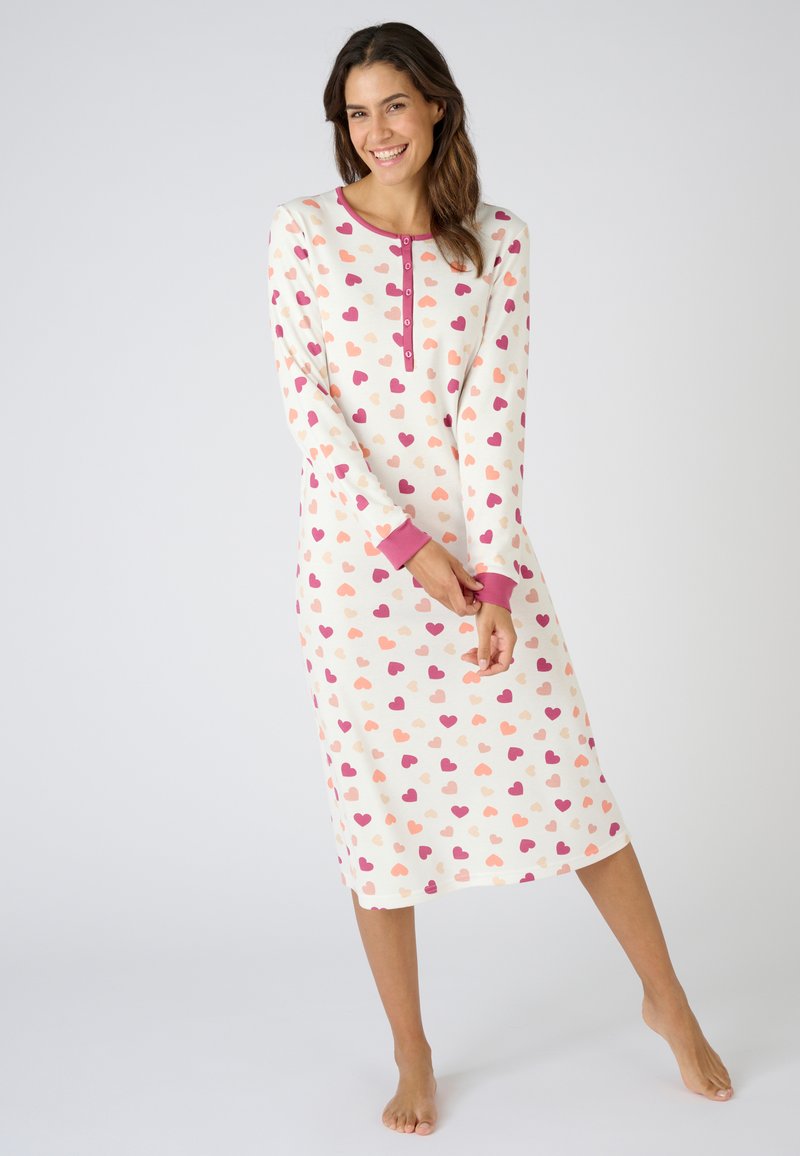 Maglietta da notte a maniche lunghe color crema con motivo a cuori rosa e corallo. Presenta un collo rotondo e una fila di bottoni, con polsini a contrasto.