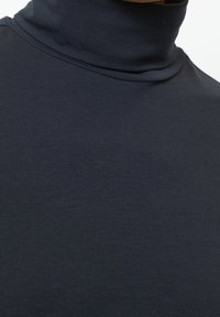 Dunkelblauer Rollkragenpullover aus weichem, dehnbarem Material mit passgenauer Form und geripptem Textil am Kragen.