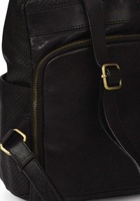 Zwarte leren tas met geperforeerde details, voorzien van een ritszak, verstelbare schouderband en messing accenten.