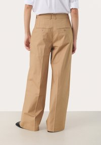 Khaki wide-leg pants made of smooth cotton fabric, featuring rear pockets with button closures and a tailored waistband.