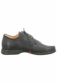 Chaussure de ville en cuir noir avec un bout arrondi, un profil bas et un laçage minimal. Présente une texture lisse et un accent rouge subtil près du talon.