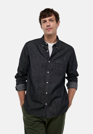Chemise en denim foncé avec un col à bouton, poche poitrine et manches retroussées. Caractérisée par un tissu texturé avec des boutons blancs contrastants.