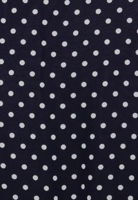 Tmavě modrá látka s opakujícím se vzorem bílých puntíků. Měkká textura s rovnoměrně rozmístěnými kruhy po celé ploše.