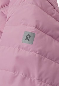 Giacca imbottita in morbido tessuto rosa, caratterizzata da un motivo a zigzag e un'etichetta grigia quadrata con un 'R' stilizzato sulla manica.