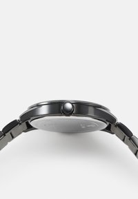 Czarny zegarek na rękę z elegancką okrągłą kopertą, teksturowaną koronką i metalową bransoletą. Charakteryzuje się minimalistycznym designem z polerowanym wykończeniem.