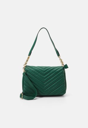 Bolso de mano acolchado verde con patrón de chevron, detalles de cadena dorada y dos correas de hombro ajustables sobre fondo blanco.