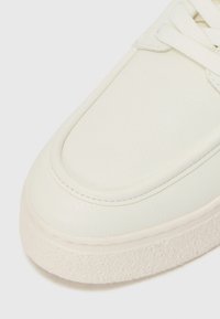 Cremfarbene Leder-Sneaker mit strukturierter Oberfläche, glattem, abgerundetem Zehenbereich und strukturiertem weißen Gummiausgang. Die Schnürsenkel entsprechen der Schuhfarbe.