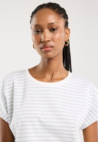 Balta trumpomis rankovėmis T-shirt maikutė su šviesiai mėlynomis horizontaliomis juostelėmis, apvalia iškirpte ir minkšta audinio tekstūra.