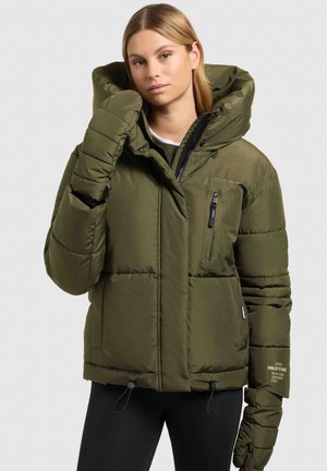 Olivzaļš pūkains jaciņa ar lielu kapuci, rāvējslēdzēja krūšu kabatu, elastīgiem aprocēm un aukliņu jostas malā; viss ar šūtu tekstūru.