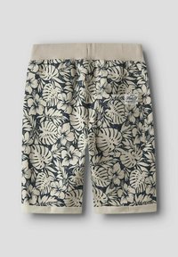 Shorts beiges avec un motif floral sombre, featuring des hibiscus et des feuilles. Taille élastique avec un dessus en tricot plat, et ourlet cousu.