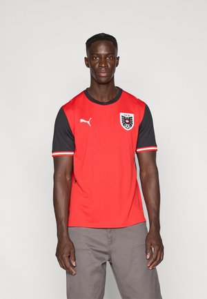 Piros sportmez fekete ujjal, fehér Puma logóval és OFB emblémával. Sima anyagból készült, az ujjakon kontrasztos csíkokkal.