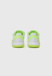 Sneakers bianchi con accenti verde brillante sul tallone e sulla suola, caratterizzati da una superficie testurizzata e cinturini regolabili in velcro.