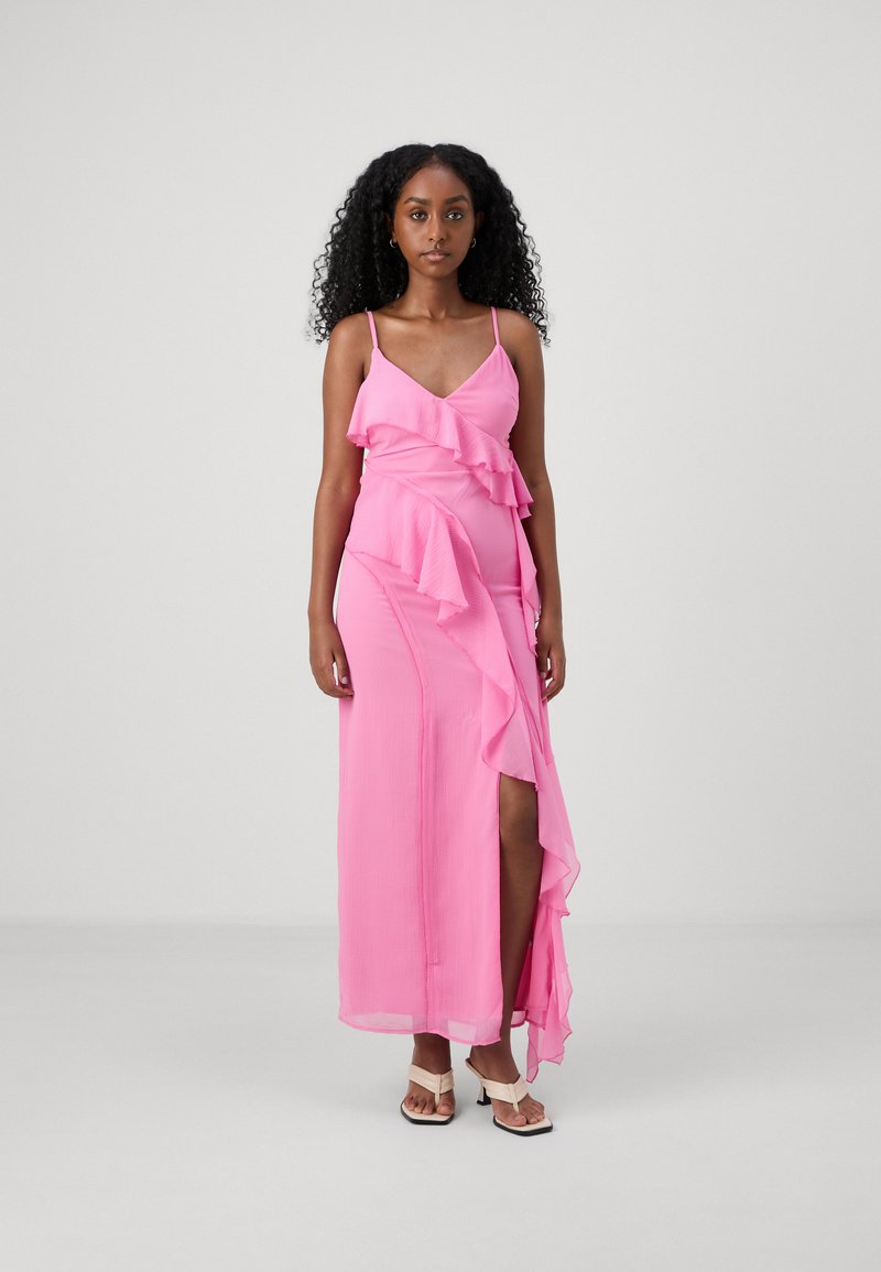Pink maxi dress with ruffle detailing, spaghetti straps, and a thigh-high slit. Made of lightweight fabric with a smooth texture.