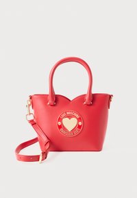 Borsa a mano sintetica rossa con forma strutturata, accessori in oro, emblema a forma di cuore e doppi manici. Include una tracolla staccabile.