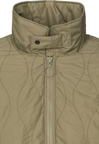 Veste matelassée à col montant vert olive avec une tirette de fermeture éclair ronde et une sangle pressionnée au niveau du cou.