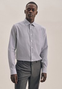 Gestreepte overhemd met knopen in lichtblauw en wit, gemaakt van stof met een gladde textuur; heeft een kraag en lange mouwen. Grijze broeken zichtbaar.