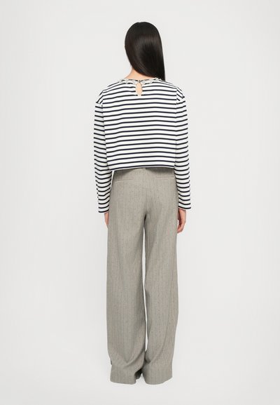 Cropped long-sleeve shirt with navy and white stripes, keyhole back detail; paired with light grey pinstriped wide-leg trousers.