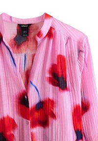 Lyserød plisseret bluse med blomsterprint i rød, blå og sort. Har krave og knapper foran. Fremstillet i let, tekstureret stof.