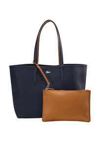 Sac fourre-tout bleu marine avec deux poignées et une petite pochette en cuir marron attachée avec fermeture éclair. Logo crocodile argenté sur le sac.