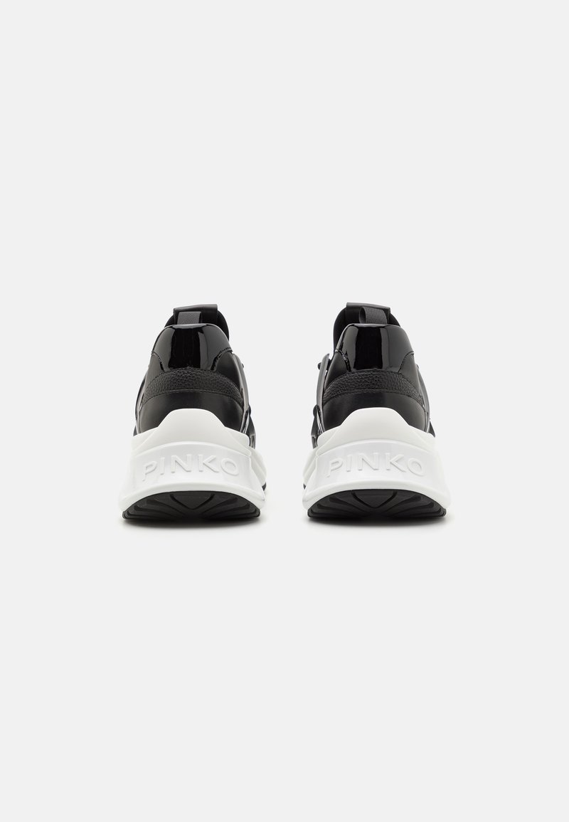 Baskets noir et blanc avec une finition brillante, dotées d'un dessus rembourré, de languettes et de semelles blanches avec logo. Semelles extérieures en caoutchouc texturé.