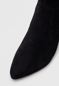 Black suede ankle boot with a pointed toe and smooth texture; features a sleek silhouette without visible hardware or embellishments.