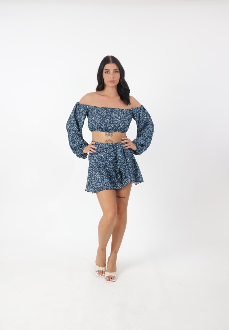 Top corto sin mangas y minifalda a juego en azul con un patrón floral. Tejido ligero, mangas largas con puños elásticos.