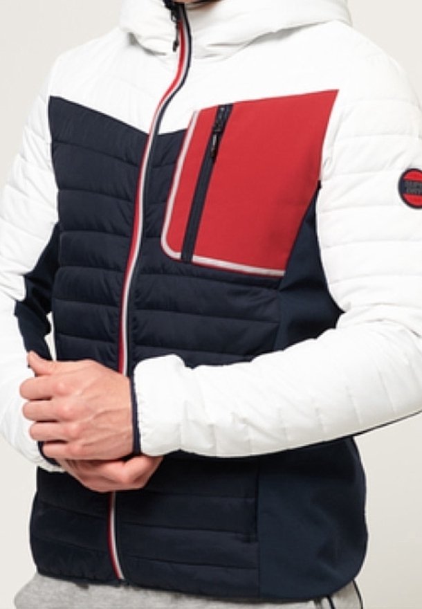 Polstret jakke med hvid hætte og ærmer, navy krop, rød brystlomme og kontrasterende røde og hvide detaljer. Har lynlås lukning.