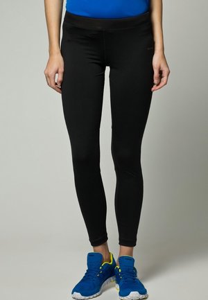 Leggings de sport noirs avec un ajustement serré, une texture lisse et une large ceinture, assortis à des chaussures de sport bleues avec des accents jaunes.