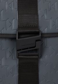 Gray textured material featuring a geometric pattern with a black strap and buckle closure. The buckle has "KARL LAGERFELD" engraved.