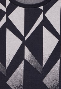 Baumwoll-T-Shirt mit einem abstrakten geometrischen Muster in Marineblau und Hellgrau, das dreieckige Formen und verschiedene Punkttexturen aufweist.