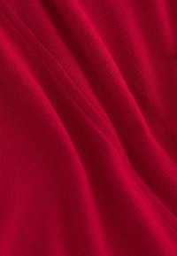 Tessuto di lana rossa lavorato a maglia con una trama liscia, caratterizzato da sottili variazioni nel motivo e una finitura morbida.