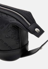 Bolsa de cuero negro texturizado con cremallera plateada y cierre de botón a presión, con patrones decorativos en relieve en su superficie.