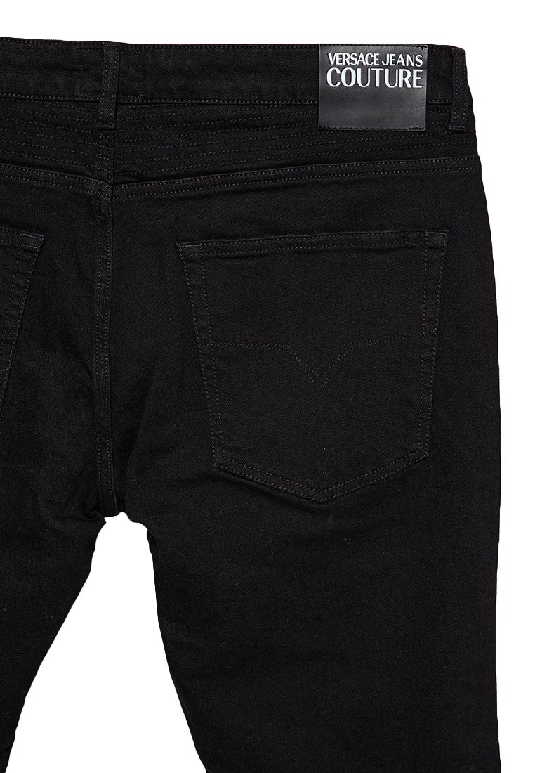 Zwarte denim jeans, achteraan gezien, met twee achterzakken en een zwart leren label met de tekst "Versace Jeans Couture" op de tailleband.