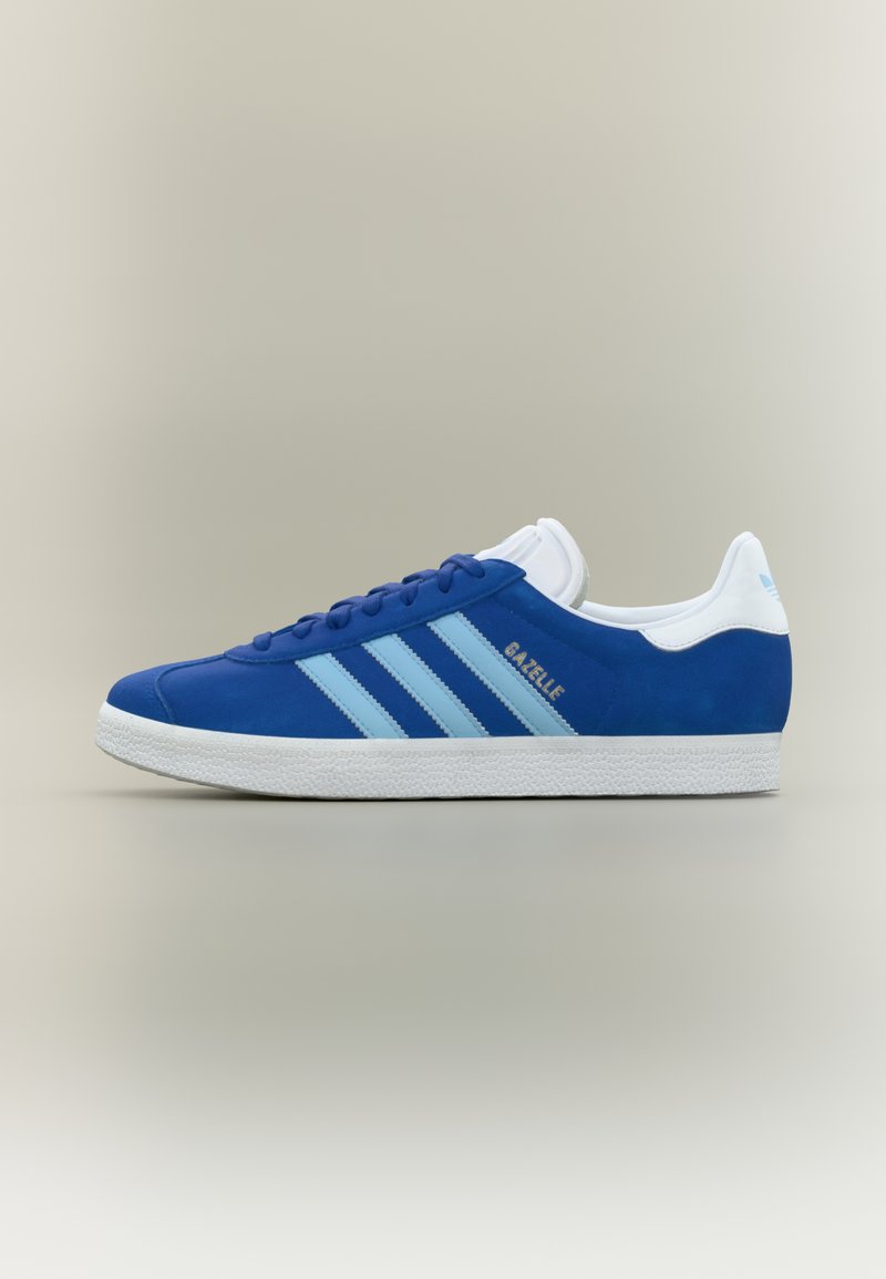 Μπλε σουέντ αθλητικό παπούτσι με ανοιχτά μπλε ρίγες, λευκές λεπτομέρειες και λαστιχένια σόλα. Διαθέτει στρογγυλεμένη μύτη και λεπτομέρεια με λογότυπο στο πλάι.