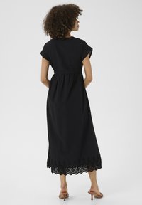 Black maxi dress with short sleeves, cinched waist, and lace trim at the hem. Lightweight fabric with a smooth texture.