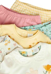 Kollektion von Kinderbekleidung mit gelben, rosa und gemusterten Oberteilen, die florale Designs und strukturierte Kragen aufweisen.
