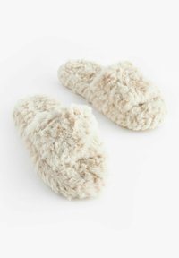 Pantofole in pelliccia sintetica beige, con una texture fluffy e design a bande incrociate. La suola è piatta per comfort e facilità d'uso.