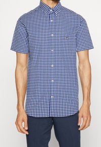 Camicia a maniche corte con bottoni in fantasia a scacchi blu e bianchi, realizzata in tessuto traspirante, con taschino sul petto e colletto button-down.