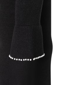 Schwarzer Pullover mit gestrickter Textur, gerippten Bündchen und einer dekorativen Linie aus weißen Perlenakzenten entlang des Bündchenrandes.