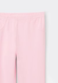 Pantalones deportivos de color rosa claro con cintura elástica, bolsillos laterales y una textura suave. Hay aberturas en los puños para un detalle adicional.