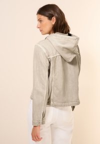 Light gray denim jacket with a hood, featuring buttoned cuffs and a relaxed fit. Back view shows a slight sheen and soft texture.