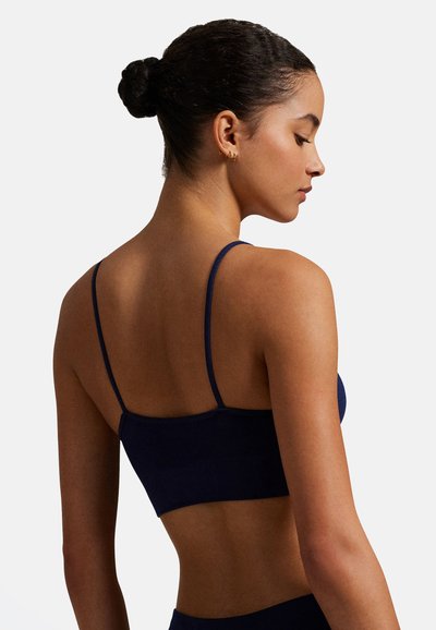 Tmavě modrý bralet s nastavitelnými tenkými ramínky, bezešlou strukturou a přiléhavým střihem, který zdůrazňuje hladká záda a žebrovaný detail.