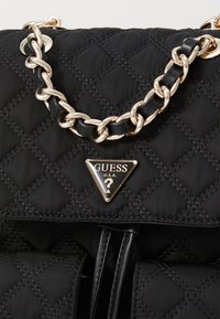 Schwarze, gesteppte Handtasche aus Nylon, mit einem goldenen Kettenhenkel und goldenen, markierten, dreieckigen Logodetails sowie schwarzen Lederakzenten.
