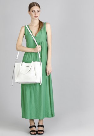 Abito maxi in tessuto verde, taglio A-line, abbinato a una borsa in pelle bianca con motivo in rilievo, accentuato da sandali neri con cinturino.