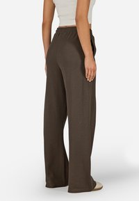 Kalhoty s širokými nohavicemi z tmavě hnědé žebrované látky, s elastickým pasem pro pohodlí, bočními kapsami a volnějším střihem.