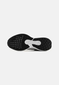 Semelle en caoutchouc noir et blanc d'une paire de baskets avec un motif de semelle texturé et un marquage "AIR" dans la zone du milieu du pied.