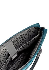 Türkisfarbene Stofftasche mit einem Reißverschluss, die ein graues Innenfutter mit einem schwarzen Blitzmuster und einem textilem Tragegurt hat.