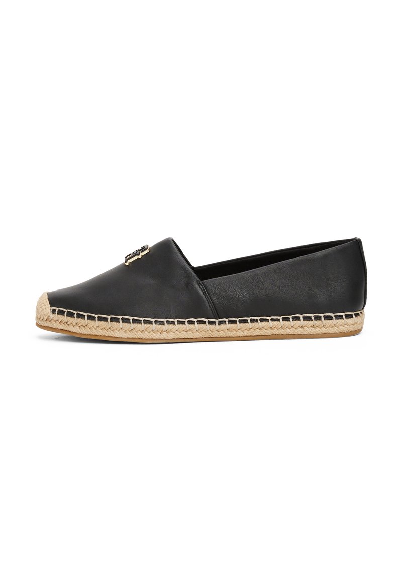 Espadrille en cuir noir à enfiler, avec une semelle en jute, un design plat et des accents métalliques à l'avant pour plus de détails.