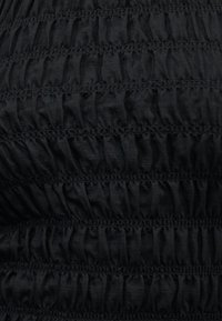 Κοντινό πλάνο μαύρου υφάσματος με οριζόντιες σειρές ραφής με πιέτες, δημιουργώντας ένα υφασμάτινο μοτίβο.