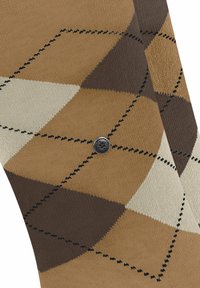 Chaussettes marron à motifs avec un design en losanges beige et marron foncé, ornées de coutures noires contrastées et d'un petit logo.